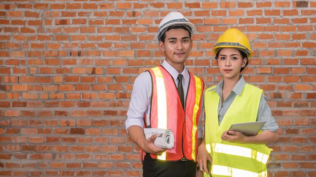 Portrait of an architect builder  and woman engineer  in front of  brick wall with copy space