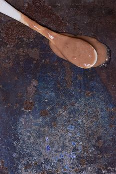 Spoon with melted ice cream on grunge background