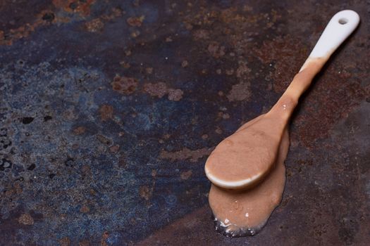 Spoon with melted ice cream on grunge background