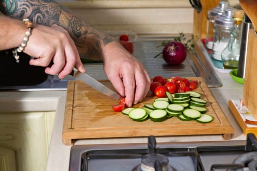 Cutting the zucchini, cherry tomatoes and red onion over a chopping board