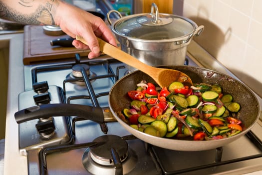 Zucchini, cherry tomatoes and red onion cooking in the pan