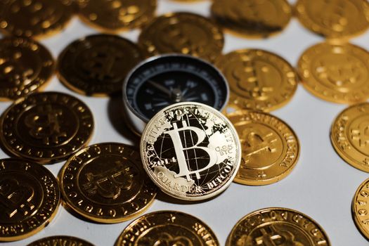 Cryptocurrency physical metal bitcoin coin on the gold bitcoins near black compass. Money concept.