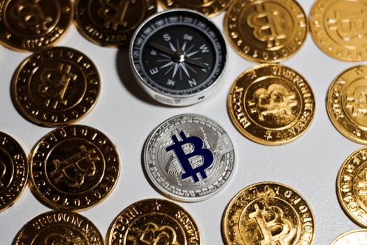 Cryptocurrency physical metal bitcoin coin on the gold bitcoins near black compass. Money concept.
