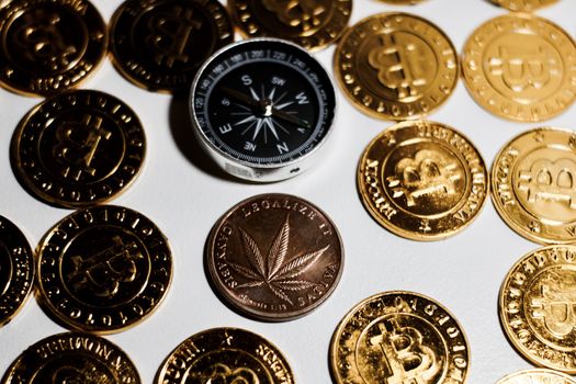 Brass physical marijuana metal coin on the gold bitcoin coins. Money weed concept.