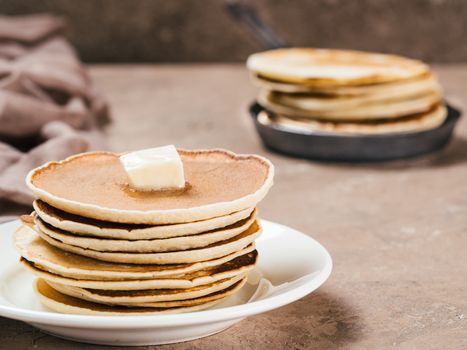 Close up view of homemade pancakes. Stack of pancakes with butter on brown concrete background.