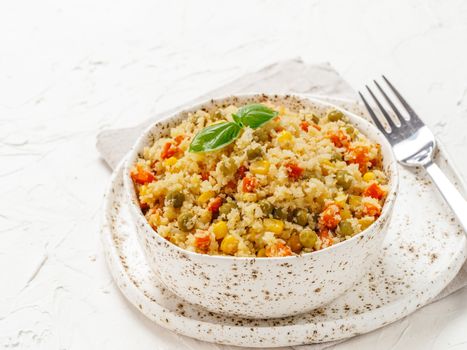Close up view of cauliflower rice with vegetables. Organic paleo Cauliflower Rice with corn, green peas and carrots on white concrete background. Copy space.