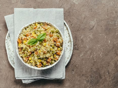 Top view of cauliflower rice with vegetables. Organic paleo Cauliflower Rice with corn, green peas and carrots on brown concrete background. Copy space.