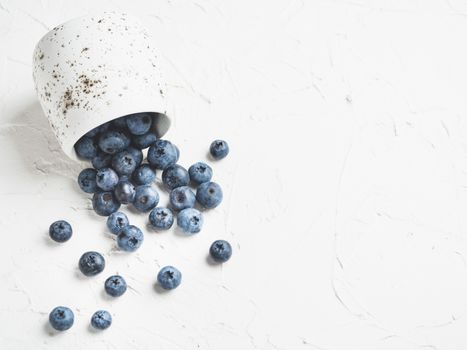 Blueberries on white concrete background. Blueberry border design. Fresh picked bilberries scattered close up. Copyspace. Closeup