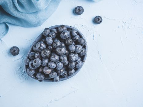 Blueberries in plate on blue background. Fresh picked bilberries close up. Copyspace. Top view or flat lay