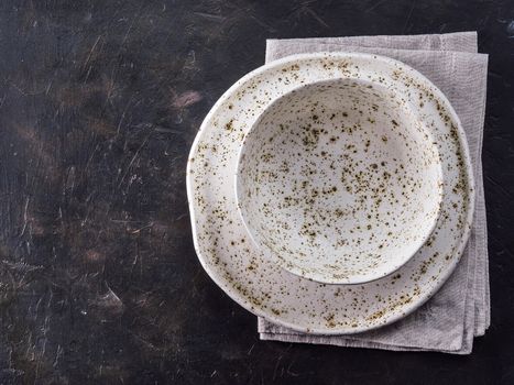 Table setting. White craft plate at dark slate table. Dark food background. Top view copy space.