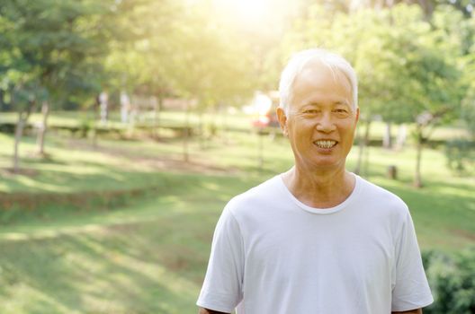 Portrait of white hair Asian old man smiling, standing at outdoor park in morning. 