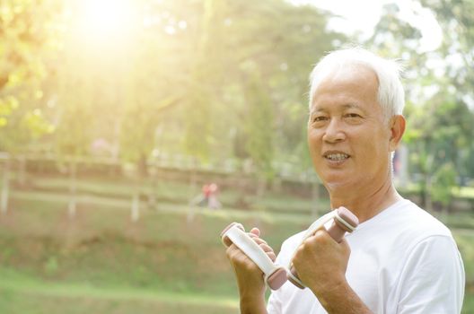 Portrait of healthy white hair Asian old man holding dumbbell at outdoor park in morning.