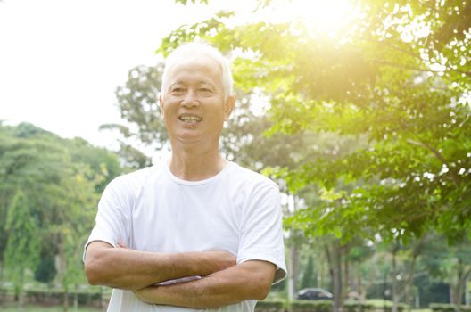 Portrait of healthy gray hair Asian old man smiling and arms crossed at outdoor park in morning.