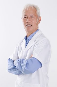 Portrait of old Asian man in lab coat smiling, standing isolated on white background.