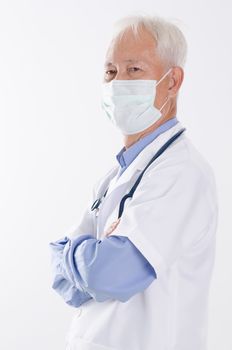 Portrait of Asian senior medical doctor in face mask arms crossed, standing isolated on white background.