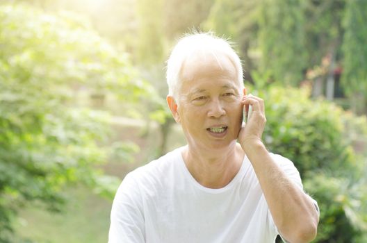 Portrait of gray hair Asian old people talking on smart phone, standing at outdoor park in morning. 