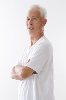 Portrait of side view old Asian man arms crossed standing isolated on white background.