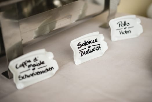 Signs for barbecued meat food in Italian and German.