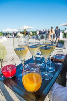 Waiter serving champagne and fruit juice on a tray, luxury diner