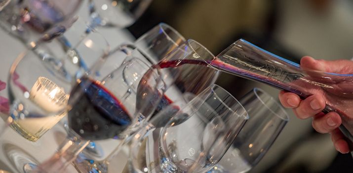 Sommelier pouring wine into glass from mixing bowl at luxury diner