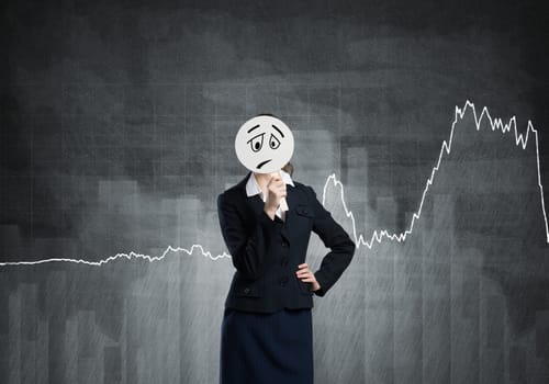 Businesswoman and graphs at background hiding her face behind mask