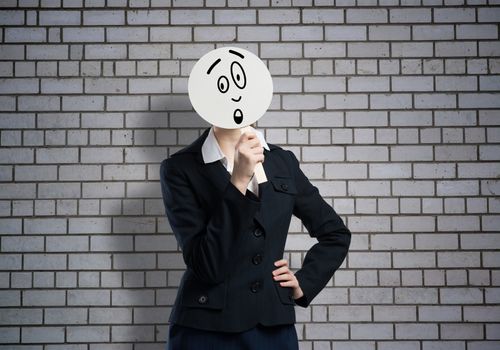 Businesswoman hiding her face behind round banner with sad smiley