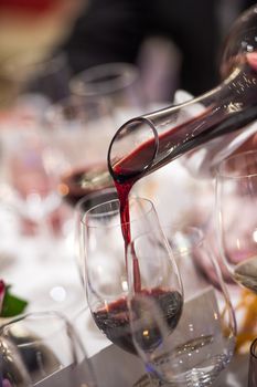 Sommelier pouring wine into glass from mixing bowl at luxury diner