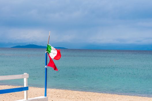Little italian flag on the beach in a cloudy day of autumn - platamona - sardinia