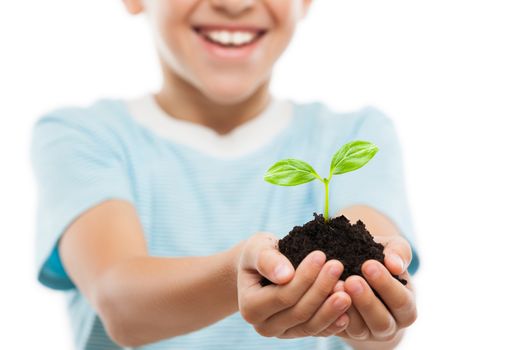 New life concept - handsome smiling child boy hand holding small green plant sprout leaf growth at dirt soil heap white isolated