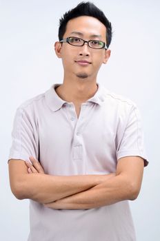Portrait of cool Asian man arms crossed, standing isolated on plain background.