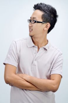 Portrait of happy Asian man arms crossed looking at side, standing isolated on plain background.