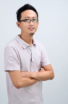 Portrait of happy Asian man arms crossed looking at camera, standing isolated on plain background.