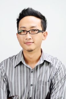 Portrait of cool Asian businessman smiling, standing isolated on plain background.