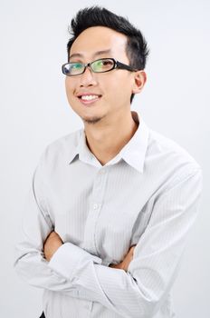 Portrait of happy Asian business man smiling and looking at camera, standing isolated on plain background.