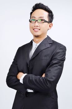 Portrait of smart Asian businessman arms crossed smiling and looking at camera, standing isolated on plain background.