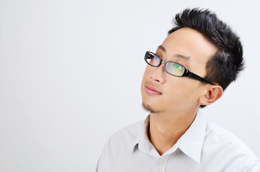 Portrait of Asian business man thinking and looking at side, standing isolated on plain background.