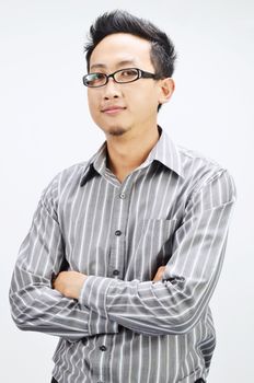 Portrait of cool Asian businessman arms crossed and smiling, standing isolated on plain background.