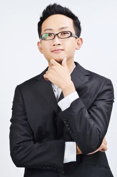 Portrait of smart Asian businessman arms crossed, thinking and looking at camera, standing isolated on plain background.