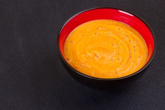 Pumpkin and carrot soup with cream and parsley on dark wooden background Top view Copy space