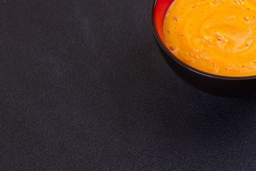 Pumpkin and carrot soup with cream and parsley on dark wooden background Top view Copy space