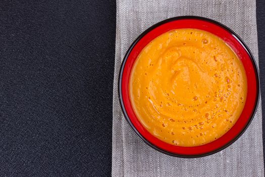 Pumpkin and carrot soup with cream and parsley on dark wooden background Top view Copy space