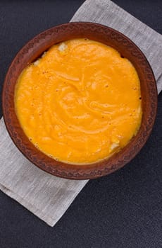 Pumpkin and carrot soup with cream and parsley on dark wooden background Top view Copy space