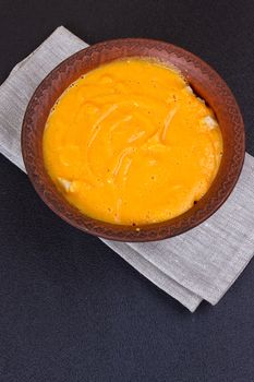 Pumpkin and carrot soup with cream and parsley on dark wooden background Top view Copy space