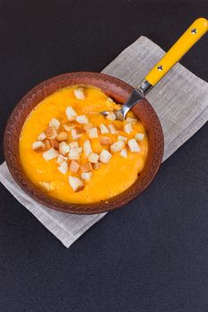 Pumpkin and carrot soup with cream and parsley on dark background Copy space