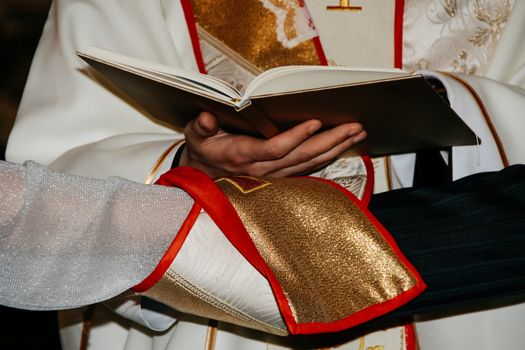 Priest holding bible above hands of bride and groom during wedding ceremony in christian church