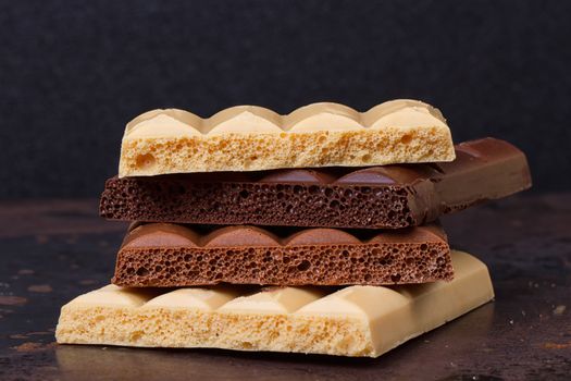 stack of different kind porous chocolate pieces on a dark background.