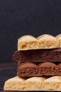 stack of different kind porous chocolate pieces on a dark background.