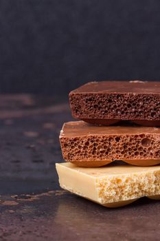 stack of different kind porous chocolate pieces on a dark background.