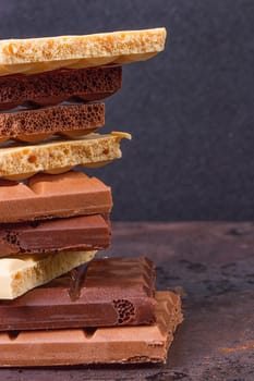 stack of different kind porous chocolate pieces on a dark background.
