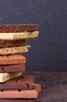 stack of different kind porous chocolate pieces on a dark background.